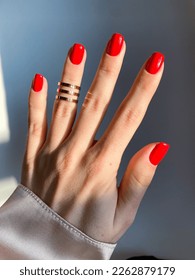 Beautiful nails manicure photo. Red color top nail polish. Female hand, rings, closeup photo, aesthetics. Manicure design, square nail shape. Luxury style, Creative beauty photo, Woman hand