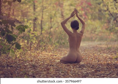 Beautiful Naked Woman Sitting In A Yoga Pose Outdoors In A Fall Park