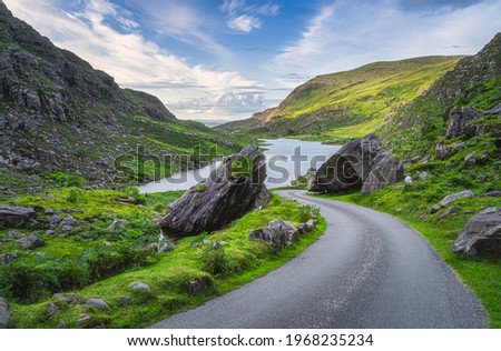 Beautiful and narrow winding road going between two halves of split rock or boulder in Gap of Dunloe, Black Valley, MacGillycuddys Reeks mountains, Ring of Kerry, Ireland