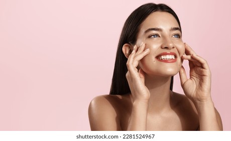 Beautiful natural girl smiling, rubbing her face with facial cleanser for glowing healthy skin, looking happy. Curly young woman showering, using skincare hydrating products, pink background. - Powered by Shutterstock