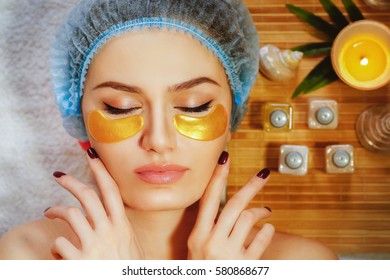 Beautiful natural girl woman in the spa salon,It makes a face mask,facial rejuvenation procedure,spa treatments.Visit a beautician.Cosmetology.Collagen facial mask, mask for the skin around the eyes. 