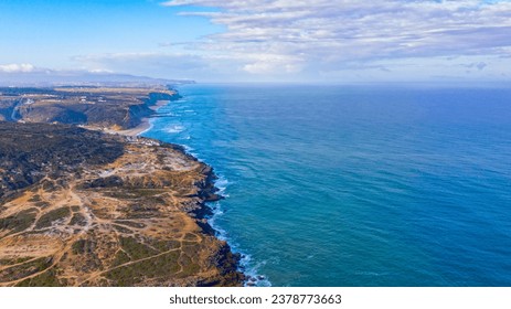 Beautiful natural landscape with ocean rocky shore, top view. Drone view over long rocky coastline in Ericeira, Portugal, on summer sunny day.  Aerial view over Scenic ocean scape with clouds on sky - Powered by Shutterstock