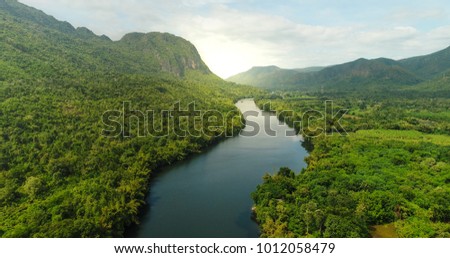 Beautiful natural scenery of river in southeast Asia tropical green forest  with mountains in background, aerial view drone shot