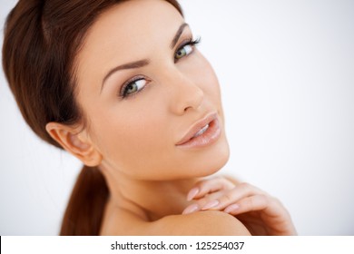 Beautiful natural sensual woman posing looking over her shoulder at the camera with a seductive look, studio portrait with bare shoulders