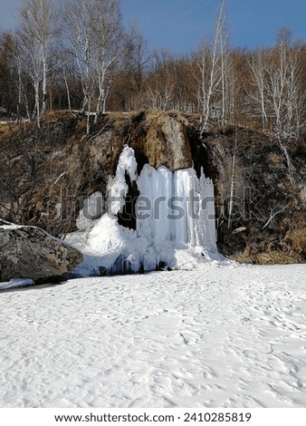 Beautiful natural waterfall in winter, ice waterfall flowing down cliff, spring drops, melting snow, natural attraction. High quality photo