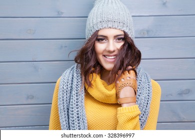 Beautiful Natural Young Smiling Brunette Woman Wearing Knitted Sweater, Leather Gloves, Scarf And Hat. Covered With Snow Flakes. Fall And Winter Fashion Concept.