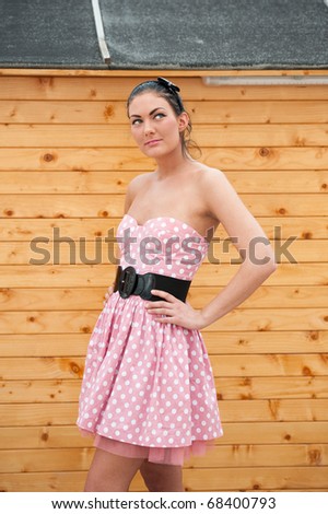 Beautiful and natural young woman wearing a modern pink dress with accessory like belt and headband.