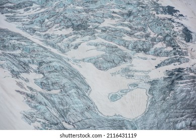 Beautiful nature background of glacier tongue with cracks closeup. Colorful natural backdrop of glacier with icefall pattern. Scenic nature texture of mountain glacier surface with fissures close up.