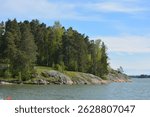 Beautiful nature, beautiful beach with yellow sand, small waves, green trees, fir trees and brown stones. The embankment of the Gulf of Finland in Espoo city, Varkaus.