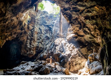 Beautiful Nature Of A Cave With Light Coming Through Hole. Woman Standing In Cave Sunbeams