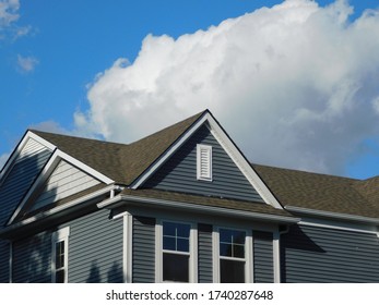 Beautiful new blue house with brown roof against bright clouds in sky