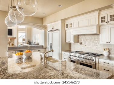 Beautiful New Kitchen Interior With Island, Sink, Cabinets And Pendant Lights In New Home