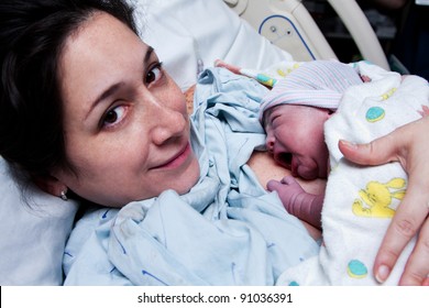 Beautiful New Mother Happy Holding Her Infant Baby After Giving Birth In Hospital.