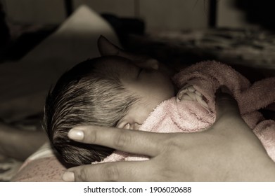 Beautiful Newborn baby boy Close up (6 days old) lying in mother lap in prenatal hospital. Kid wrapped in baby blanket (warm clothing) sleeping looking away. His mother consoling and resting her baby.