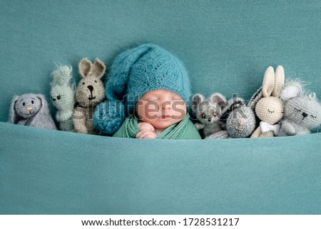 Beautiful newborn sleeping with knitted toys