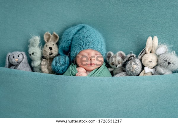 Beautiful newborn\
sleeping with knitted\
toys