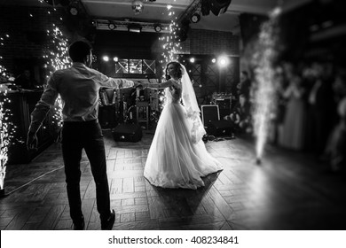 Beautiful newlywed couple first dance at wedding reception surrounded by smoke and lights and sparks b&w