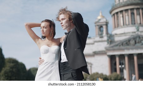 Beautiful newlyweds on background of old architecture. Action. Elegant couple of newlyweds posing on background of cathedral on sunny day. Newlyweds on windy sunny day in summer