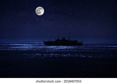 Beautiful night scene at sea. Dramatic moon over sea at night with silhouette of the ship