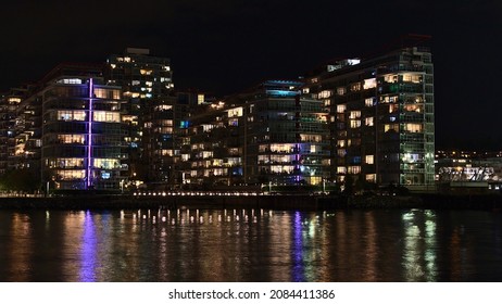 Beautiful night view of illuminated modern apartment buildings on the shore of Vancouver North, British Columbia, Canada near The Shipyards in district Lower Lonsdale with colorful water reflections. - Shutterstock ID 2084411386
