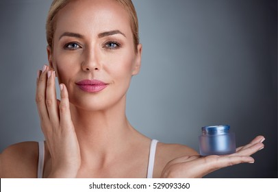 Beautiful nourished woman holding cream for her skin 