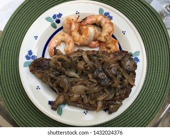 Beautiful NY Strip Steak Atop A Blueberry Designed Plate Atop A Green Round Placemat.  The Steak If Perfectly Cooked And Served With Sautéed Mushrooms And A Side Of Grilled Shrimp.