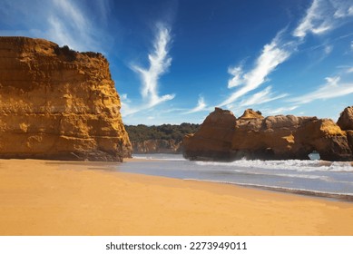 
beautiful ocean shore with clean yellow sand at sunset with a picturesque sky and cliff. summer in portugal in algarve