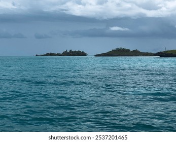 Beautiful ocean water with remote islands in background and cloudy skies. - Powered by Shutterstock