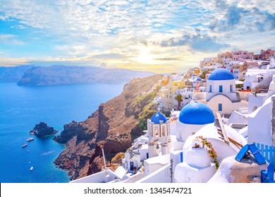 Beautiful Oia town on Santorini island, Greece. Traditional white architecture  and greek orthodox churches with blue domes over the Caldera, Aegean sea. Scenic travel background.