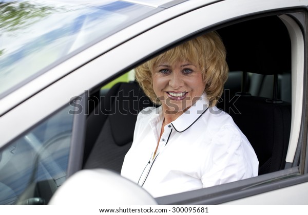 Beautiful old happy elderly driver woman 55-60 years\
in jacket Driving a\
Car