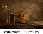 Beautiful old lute and antique books on a rustic old wooden shelf. 