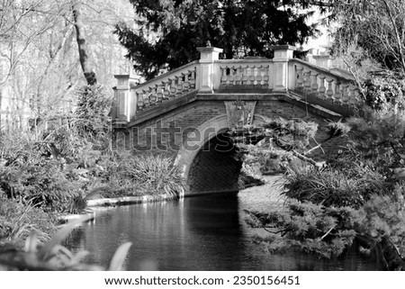 Beautiful old stone bridge with railing over clean river in preserve, natural nature consisting of arched stone ancient bridge over long river, over deep blue river standing decrepit stone bridge