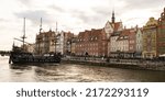 Beautiful old town of Gdansk over Motlawa river Vintage ship pirate caravels sailing on Motlawa river with historic port Crane in Old Town on background. Gdansk, Poland. This ship imitating XVII