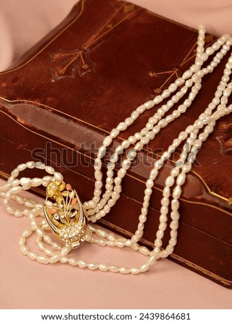 Beautiful old vintage Perl necklace with golden flowers locker on brown wooden box and pink background. Antique jewelry