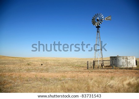 a beautiful old windmill water tower in a field on a beautiful summer day with a cloudless blue sky in a field