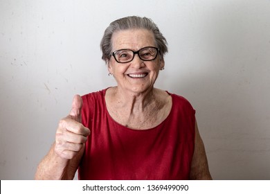 Beautiful old woman with two tumbs up. Cheerful caucasian senior showing two thumbs up on white background.