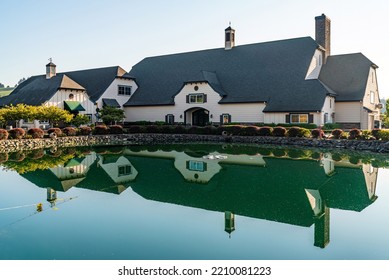 Beautiful Old World Tudor Architectural Style Building With Reflection In Calm Still Pond Water.