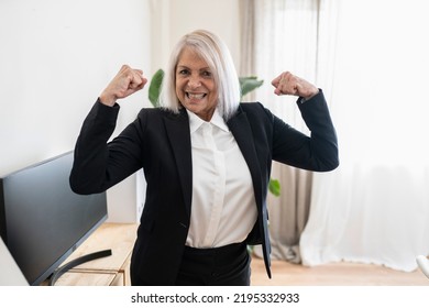 Beautiful Older Woman, Businesswoman Standing In Office Showing Arm Muscles Smiling Proud. Female Boss Empowerment Concept.