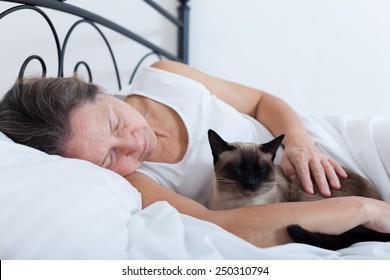 Beautiful Older Woman With   Cat Sleeping On   Bed.