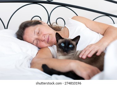 Beautiful Older Woman With   Cat Sleeping On   Bed.