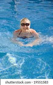 A Beautiful Older Woman In Her Sixties Is Enjoying A Relaxing Swim In The Swimming Pool During Her Vacation Or Retirement In The Sun