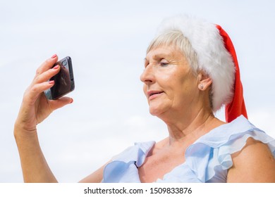 Beautiful Older Woman With Santa Hat Taking A Selfie, Happiness Concept