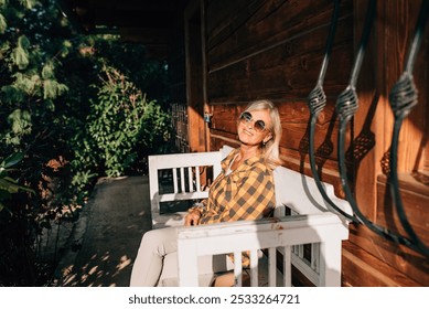 Beautiful older women is sitting in front of her cabin, enjoying autumn sun rays on her face. - Powered by Shutterstock