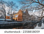 The beautiful orange buildings by the channel and snowy trees in Uppsala, Sweden in winter