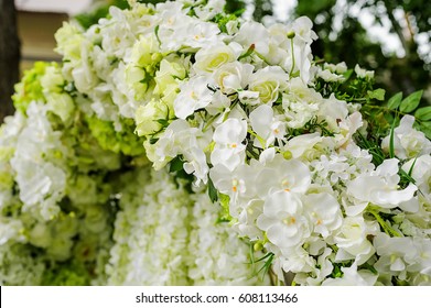 Beautiful Orchids And Roses Wedding Arch, Close-up. White And Green Color Palette. Spring Or Summer Outdoor Wedding.