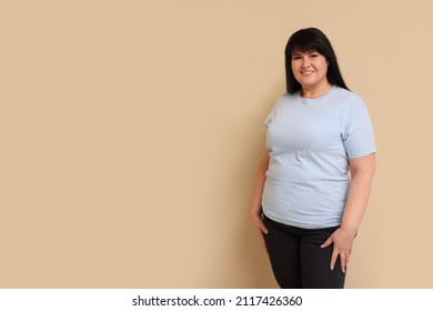 Beautiful overweight mature woman with charming smile on beige background. Space for text - Shutterstock ID 2117426360