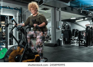 Beautiful, overweight woman push her limits during a workout, She exercises on stationary bike at the gym.	
 - Powered by Shutterstock