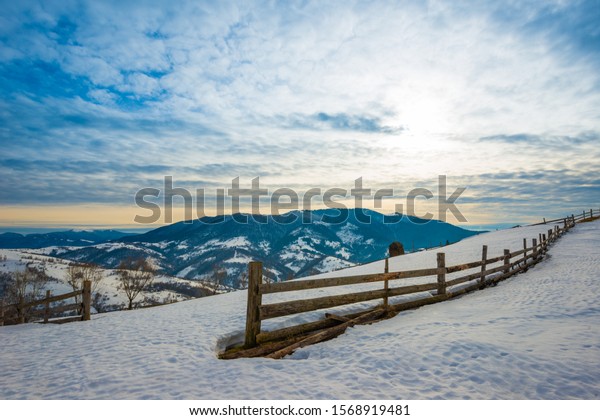 Beautiful panorama\
of the mountain ranges covered with snow and divided into hiking\
trails overlooking the cloudy sky and sunset. Place for\
advertising. Mountain tourism\
concept