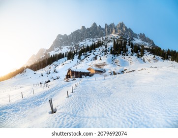 Beautiful panorama view of scenic winter wonderland mountain scenery in the Alps with traditional mountain huts illuminated in last evening light at sunset, Mühlbach am Hochkönig, Salzburg, Austria