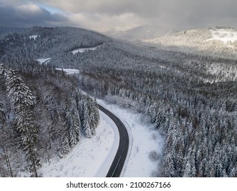 Beautiful panoramic aerial view of the winter forest, mountains and treetops in the snow. Ukrainian Carpathians in winter.
A winding mountain road. Rest and travel in winter. Shot from a drone.